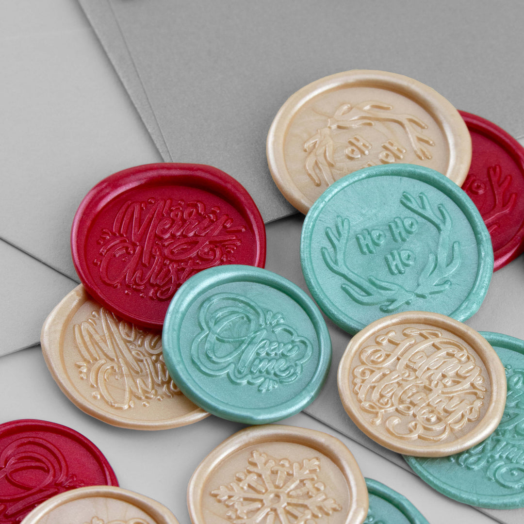 Christmas Wax Seal Stickers in 3 colours on a stack of grey envelopes